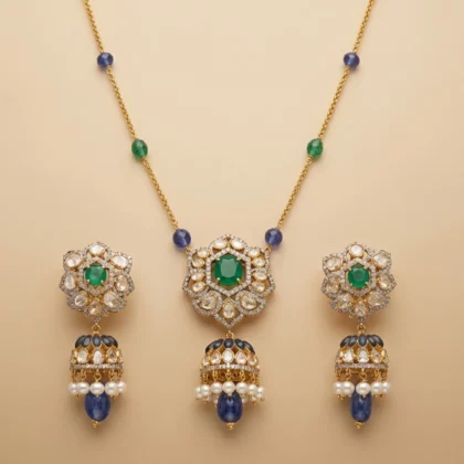 Ornate gold jewelry set featuring a central green gemstone with surrounding clear stones; includes a matching necklace with blue and green beads and three pendant earrings with pearl drops.